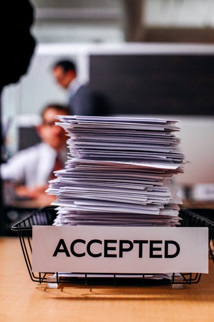 Pile of papers with 'Accepted' label in a busy office setting, highlighting information management.